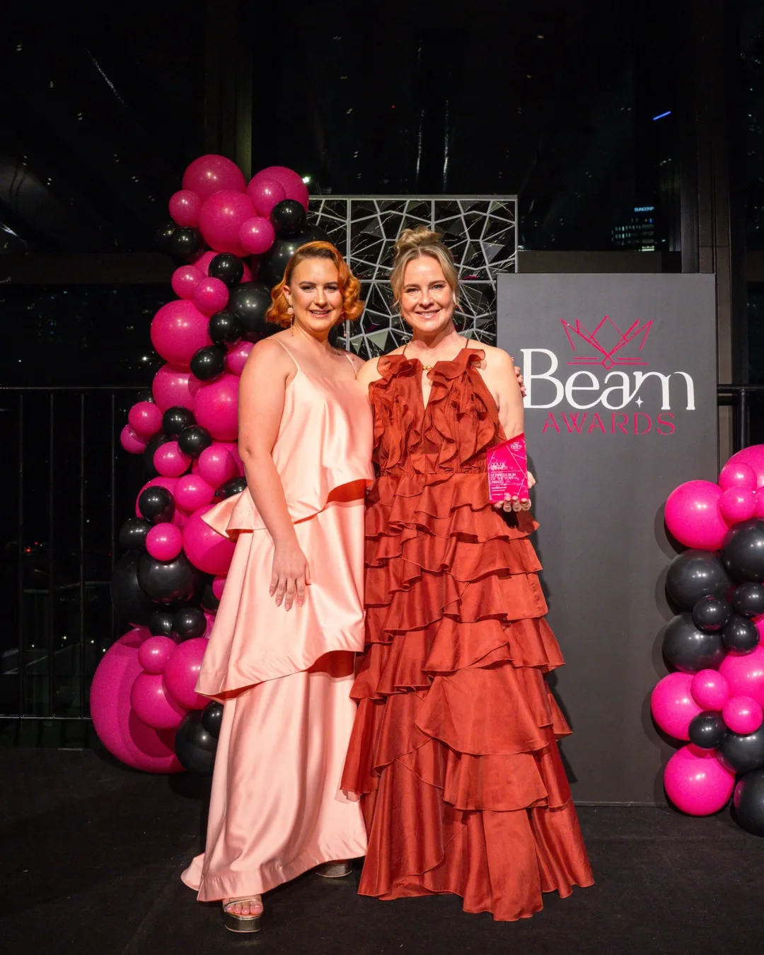 Two award winners on stage holding their trophy at the Awards Gala