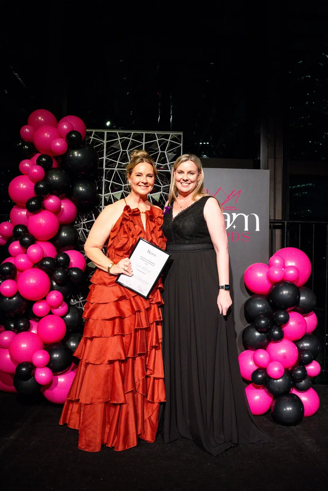 An award recipient holding a certificate beside a guest