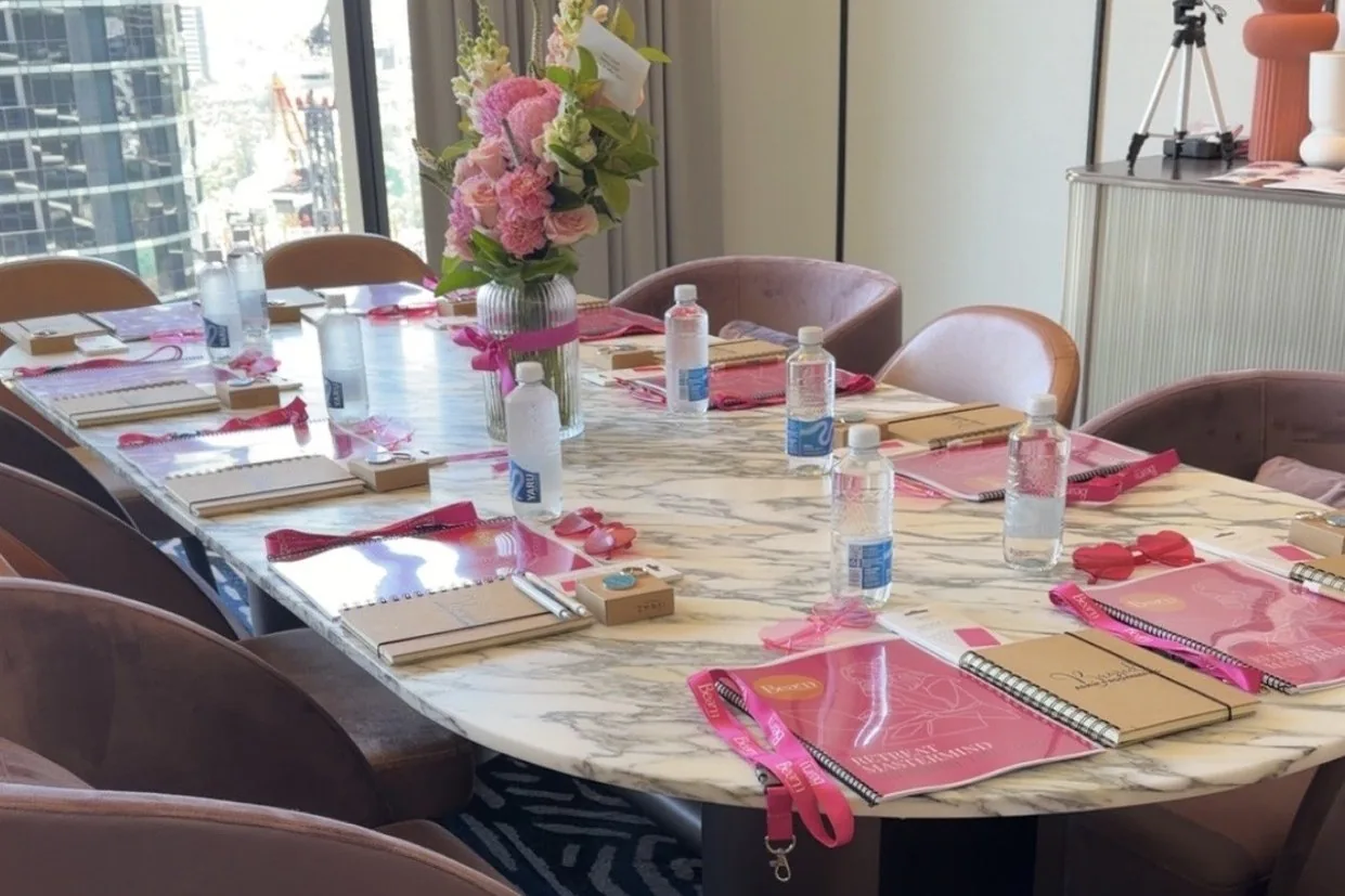 A marble table set for a small-group session with pink workbooks, notebooks and flowers