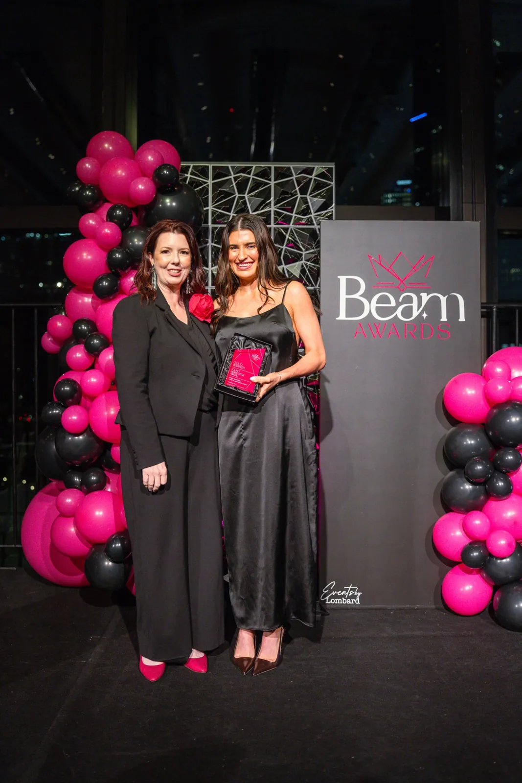 An award recipient and presenter holding a pink award
